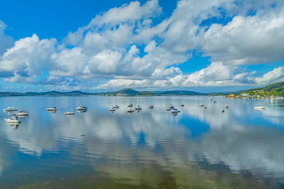 Aerial views over the bay with clouds, reflections and boats