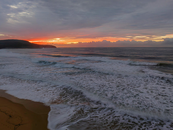 Cloud covered sunrise at the seaside in pink and blue