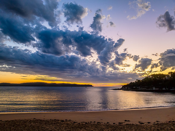 Sunrise over the ocean with clouds and a calm sea