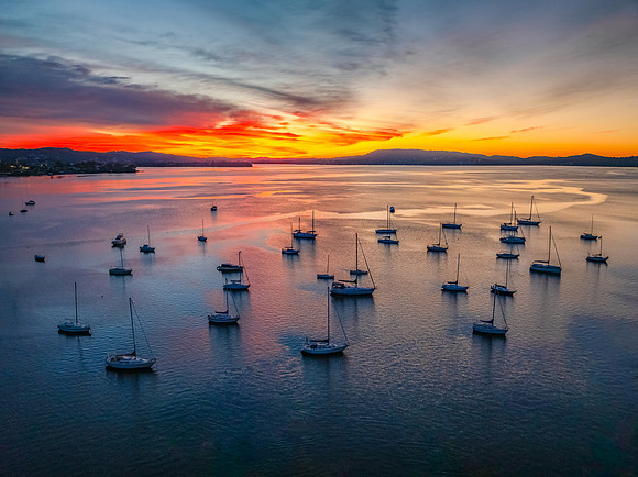 Aerial sunrise waterscape with boats and high cloud