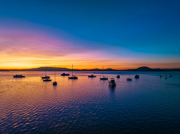 Aerial sunrise waterscape with boats and high cloud