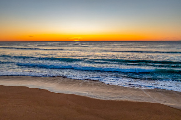 Sunrise at the seaside with clear skies and orange horizon