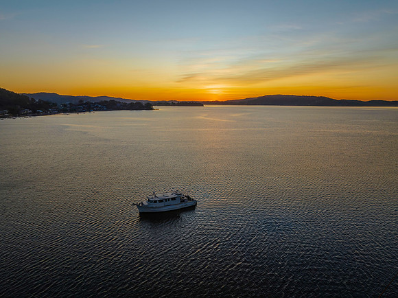 Aerial sunrise waterscape with boat and high cloud