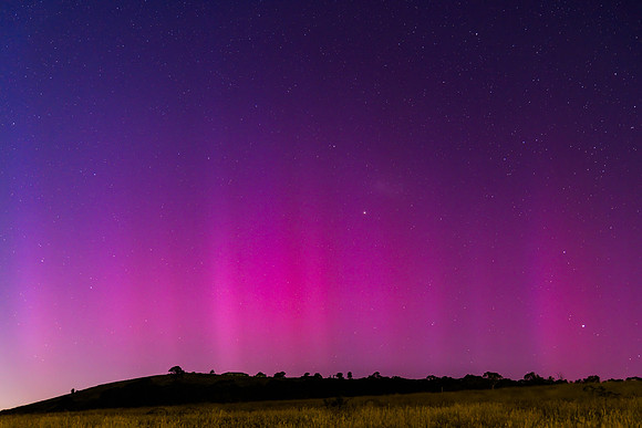 Aurora Australis display lights up the predawn sky in pinks
