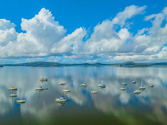 Aerial views over the bay with clouds, reflections and boats