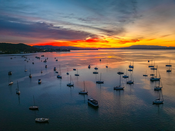 Aerial sunrise waterscape with boats and high cloud