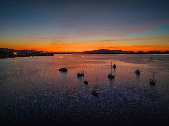 Aerial sunrise waterscape with boats and high cloud