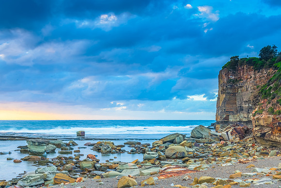 Moody sunrise seascape with clouds at the rocky inlet