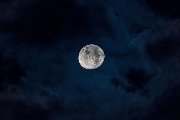 Waxing gibbous moon in the cloud covered evening sky