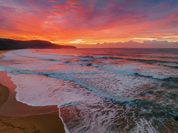 Cloud covered sunrise at the seaside in pink and blue