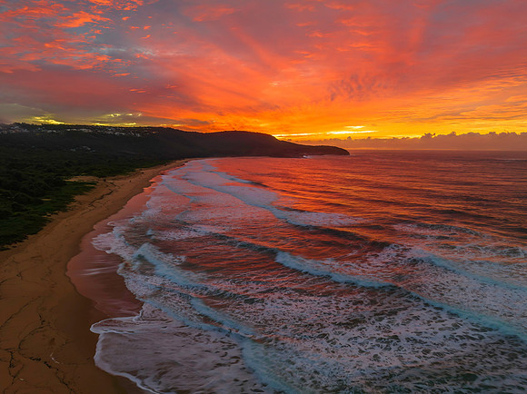Cloud covered sunrise at the seaside in pink and blue
