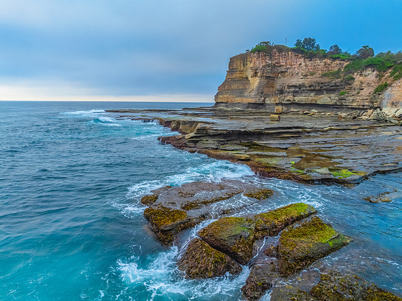 Sunrise seascape and rocky Inlet with thick fog cloud over the o