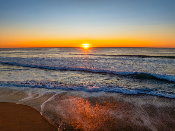 Sunrise at the seaside with clear skies and orange horizon