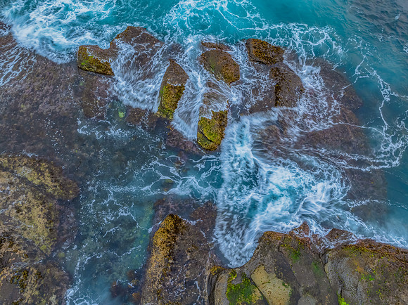 Sunrise and the blue sea washing over the rock platform