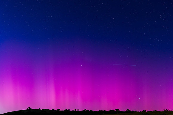 Aurora Australis display lights up the predawn sky in pinks