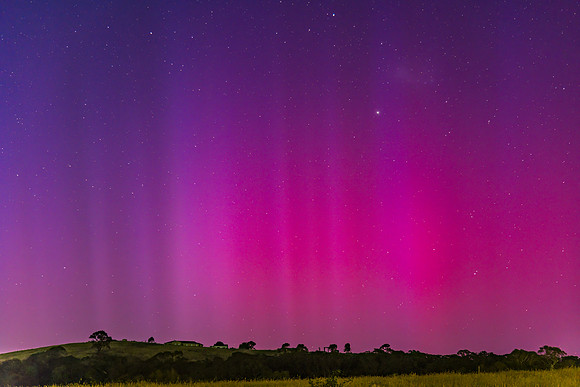 Aurora Australis display lights up the predawn sky in pinks