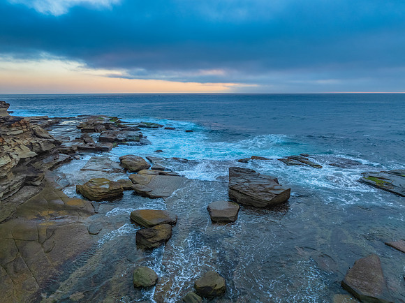 Sunrise seascape and rocky Inlet with thick fog cloud over the o