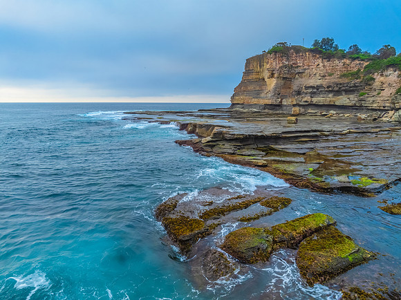 Sunrise seascape and rocky Inlet with thick fog cloud over the o