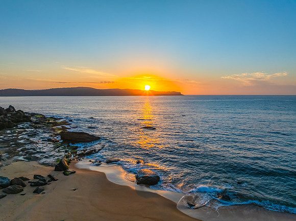 Aerial sunrise at the seaside with light scattered high cloud an