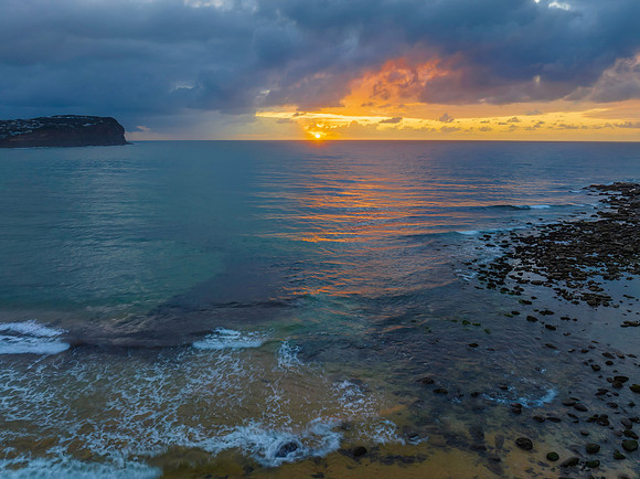Drizzly moody sunrise seascape with cloud filled sky