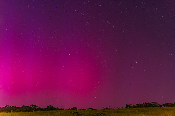 Aurora Australis display lights up the predawn sky in pinks
