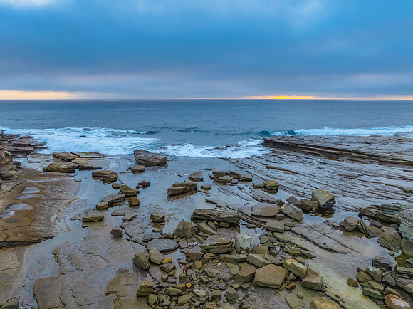 Sunrise seascape and rocky Inlet with thick fog cloud over the o