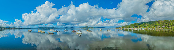 Aerial panorama over the bay with clouds, reflections and boats