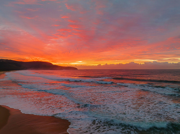 Cloud covered sunrise at the seaside in pink and blue