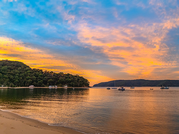 Sunrise over the bay with boats and cloud covered sky