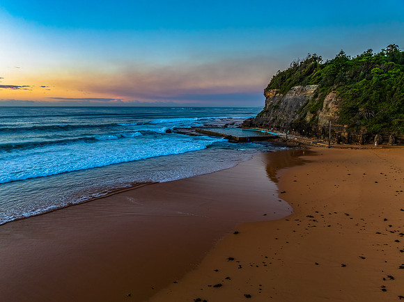 Sunrise at the beach with waves and a smattering of clouds