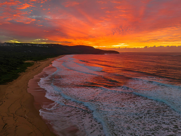 Cloud covered sunrise at the seaside in pink and blue