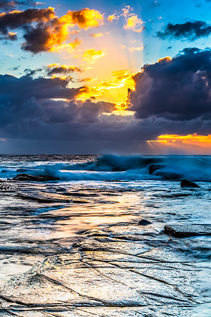Moody sunrise seascape with clouds and sunrays at the rocky inle