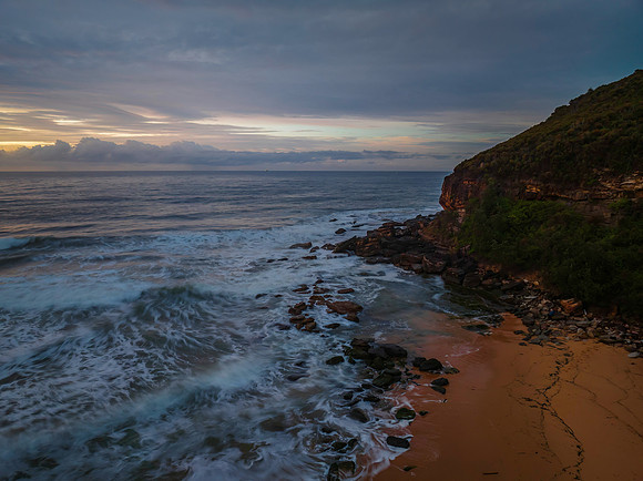Cloud covered sunrise at the seaside in pink and blue
