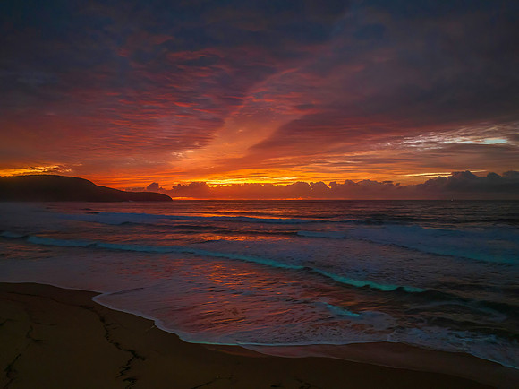 Cloud covered sunrise at the seaside in pink and blue