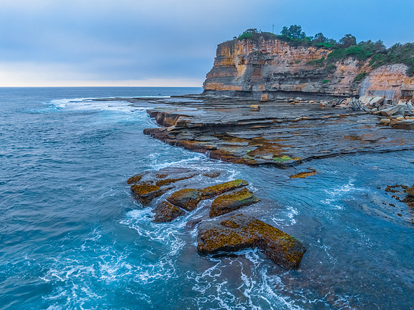 Sunrise seascape and rocky Inlet with thick fog cloud over the o
