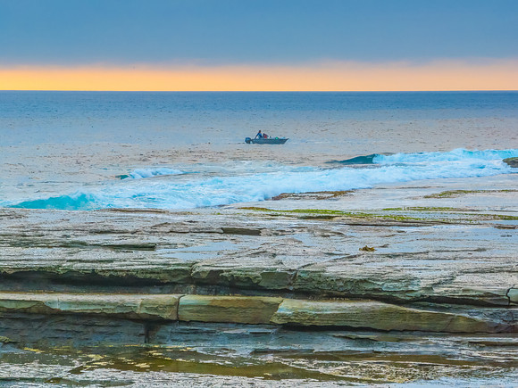Sunrise seascape and rocky Inlet with thick fog cloud over the o