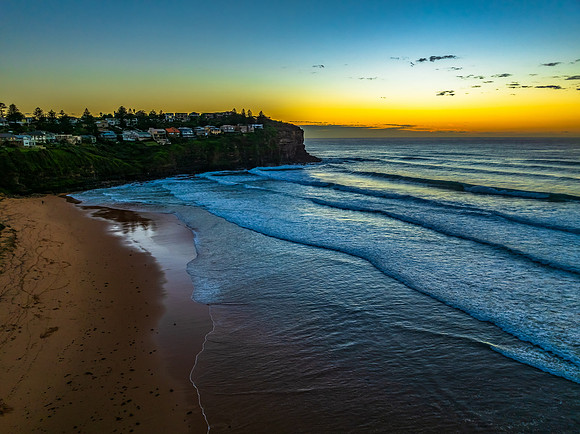 Sunrise at the beach with waves and a smattering of clouds