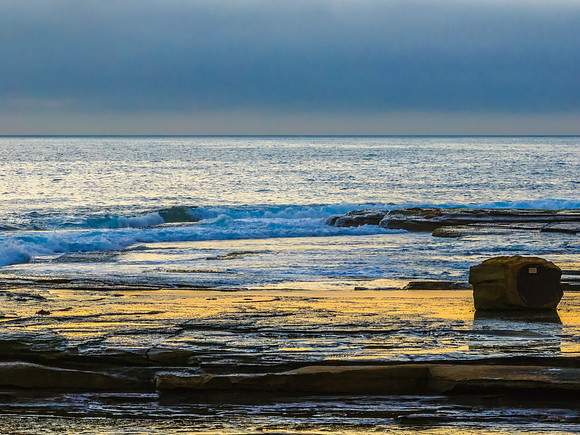 Sunrise seascape and rocky Inlet with thick fog cloud over the o