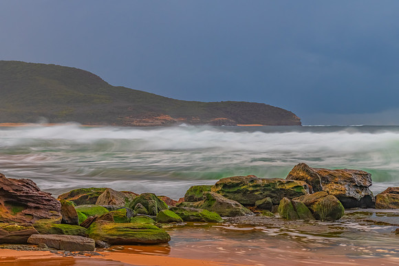 Sunrise at the seaside with rocks and rain clouds