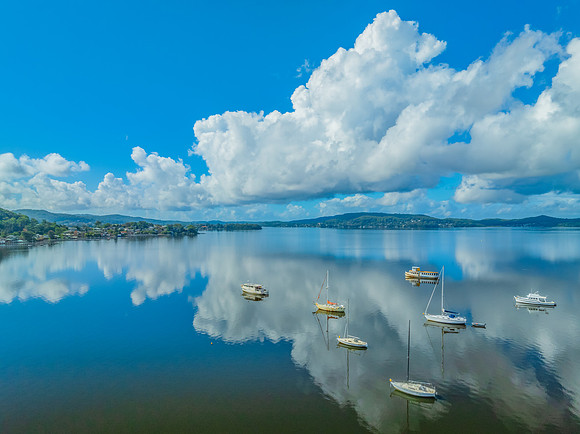Aerial views over the bay with clouds, reflections and boats