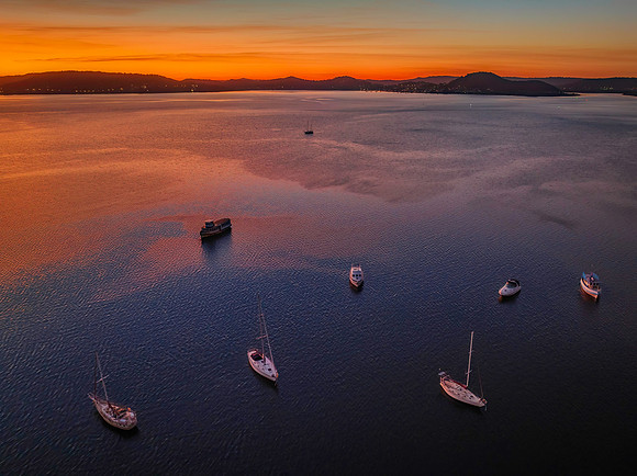 Aerial sunrise waterscape with boats and high cloud
