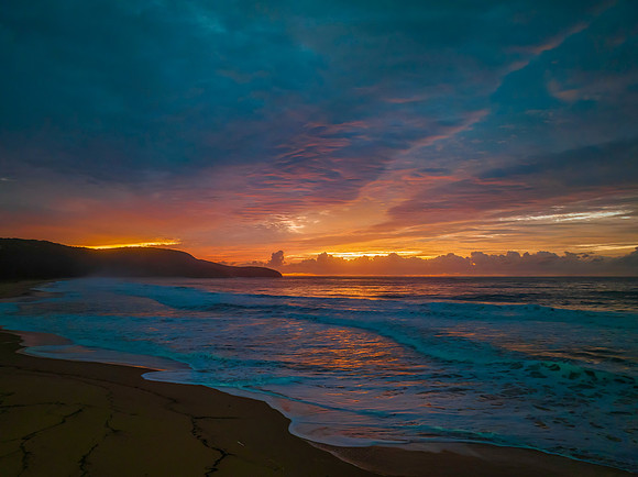 Cloud covered sunrise at the seaside in pink and blue