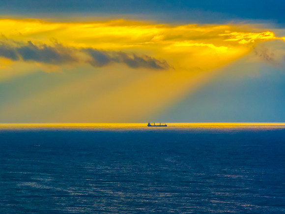 Sunrise Seascape with sunrays in the cloud covered sky and ship
