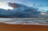 Sunrise at the seaside with rocks and rain clouds