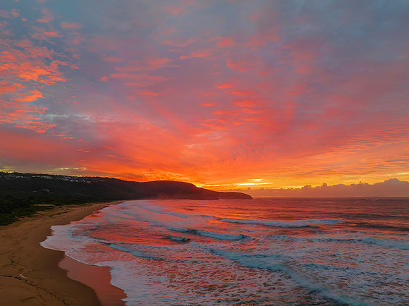 Cloud covered sunrise at the seaside in pink and blue