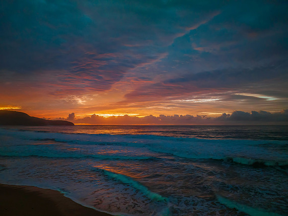 Cloud covered sunrise at the seaside in pink and blue
