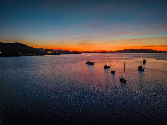 Aerial sunrise waterscape with boats and high cloud