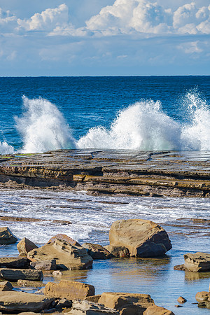 Splashes and morning seascape at rocky inlet