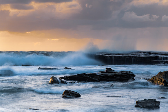 Moody sunrise seascape with clouds at the rocky inlet