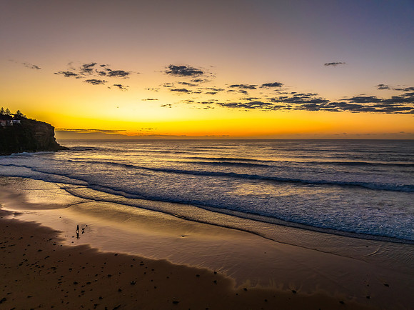 Sunrise at the beach with waves and a smattering of clouds
